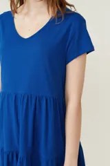Vestido corto lila con cuello en V y mangas cortas. Tiene corte holgado y dos volados en la falda.
