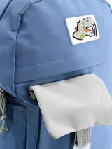 Mochila celeste con bolsillo frontal gris con cierre de hebilla y parche con diseño de dinosaurio.