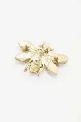 Pin metálico con forma de abeja en acabado dorado, decorado con incrustaciones de cristales tipo strass en colores verde, blanco y marrón.