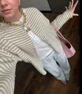 Buzo tejido a rayas horizontales rojas y blancas, con cuello tipo camisa y abotonadura frontal.