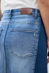 Falda larga de jean de tiro alto, con lavado medio y tajo frontal profundo. Presenta un diseño bicolor con paneles de denim de tonos ligeramente diferentes.
