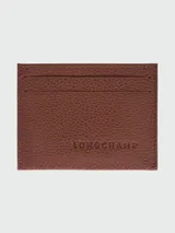 Tarjetero de cuero granulado color marrón, con tres ranuras visibles en el frente y el logo de Longchamp grabado en el centro.