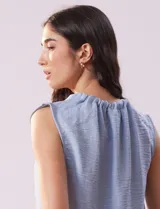 Blusa sin mangas color beige, de crepe. Cuello a la base con frunce, apertura ojal y botón.