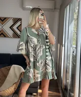 Vestido corto color verde con estampado de hojas en blanco y negro, escote con lazo y mangas tres cuartos acampanadas. Tiene dos volados en la falda.