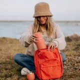 Mochila matera color naranja, diseñada para el transporte de termo y mate, con divisiones adaptadas y bolsillos laterales.