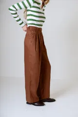 Pantalón negro de corte ancho y tiro alto, con pinzas en la cintura y bolsillos laterales.