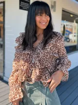 Camisa de organza color beige con estampado animal print en tonos marrones. Tiene cuello en V con volados y cierre con botones.
