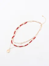 Collar dorado de tres hilos con cuentas rojas y dije colgante en forma de lágrima.