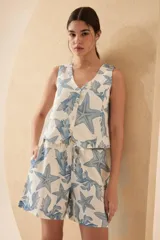Short tipo bermuda de lino color crudo con estampado de estrellas de mar y hojas en color azul.