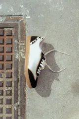 Zapatillas deportivas de cuero color blanco, negro y dorado, con cordones blancos y suela de goma.