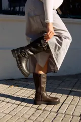 Botas de caña alta color negro, con hebillas y cierre lateral.