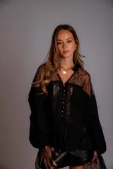 Camisa negra con encaje en la parte delantera y en las mangas, con botones dorados.