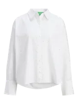 Camisa blanca de corte oversize con cuello clásico, cierre frontal con botones y pequeños brillantes plateados distribuidos por toda la prenda.