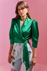 Blusa cruzada de satén color verde esmeralda, con mangas tres cuartos abullonadas y lazo lateral.