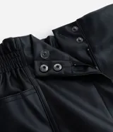 Bermuda de cuero sintético color negro, con cintura elástica, bolsillos laterales y cierre frontal con cremallera y botón.