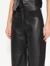 Pantalón de cuero vacuno negro con laterales en gabardina al tono. El acceso es mediante cierre metálico y botón jeanero. Incluye bolsillos estilo jeanero al frente y bolsillos plaque en la parte trasera.