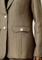 Blazer color beige con finas rayas verticales negras, de corte clásico, con solapas de muesca, cierre frontal con dos botones y bolsillos con solapa.