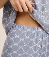 Conjunto de pijama celeste con estampado de lazos blancos, compuesto por una remera de mangas cortas y un short con cintura elástica y detalle de encaje en el ruedo.