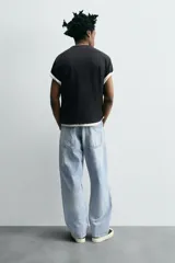Pantalón de jean gris oscuro, corte amplio, con cinco bolsillos, efecto lavado y cierre frontal con cremallera y botón.