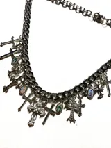 Collar de cadena gruesa plateada con dijes colgantes de cruces y medallones religiosos.