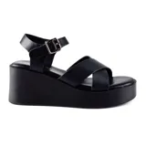 Sandalias negras con plataforma, tiras cruzadas sobre el empeine y pulsera con hebilla al tobillo.