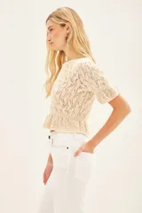 Sweater color crema tejido con punto desagujado en hilado de algodón y poliéster. Tiene ajustes en mangas y cintura, y pequeños volados en las terminaciones.