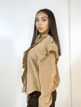 Camisa beige de pana fina con volados en los hombros y botones dorados.