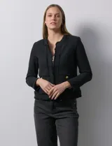 Chaqueta negra en tejido tweed de la marca Nanette. Tiene escote mao, abertura central y bolsillos delanteros. Los puños tienen apliques de botones perlados y la terminación es desflecada. Tiene forro interno.