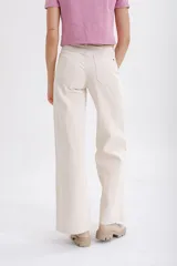 Pantalón de jean color beige, de corte palazzo, con bolsillos delanteros con botón y cintura alta.