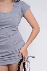 Vestido corto negro de punto, con escote redondo, mangas cortas y cordones ajustables en los laterales.