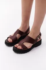 Sandalias marrones de cuero con suela track negra y hebilla plateada.