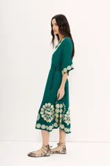 Vestido tipo túnica largo midi de viscosa color verde esmeralda con bordados florales en color crema. Tiene mangas al codo y lazo de ajuste en la cintura.