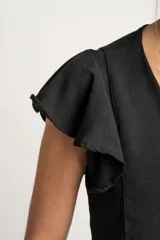 Blusa blanca con escote en V, mangas cortas con volados y cierre frontal con botones.