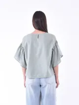 Blusa negra de mangas cortas con volados y escote redondo.