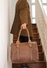 Bolso marrón de cuero con doble asa corta y cierre superior con cremallera. Tiene detalles de costuras a los lados y aplique con el nombre de la marca.