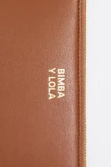 Billetera negra de piel reconstituida con estructura rígida, cierre con cremallera dorada, tirador de cordón y logo metálico Bimba y Lola. Cuenta con bolsillo interior con cremallera e interior con logo grabado.