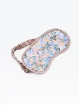 Antifaz para dormir con estampado floral multicolor y borde de satén color rosa pálido.