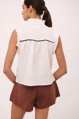 Blusa celeste de lino con cuello mao, mangas cortas con volados y cierre frontal con botones. Detalles de pespuntes y vivos en color rojo.