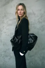Blazer negro largo con cuello solapa, manga larga con hombreras, bolsillos delanteros de vivo y cierre frontal con un botón.