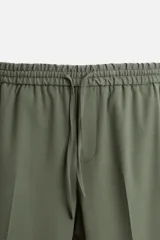 Pantalón color arena de corte recto, confeccionado en tejido elástico. Cuenta con cintura elástica ajustable con cordón, bolsillos laterales y bolsillos de vivo en la parte trasera.