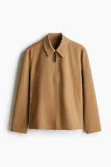 Campera color marrón claro de tejido suave con cuello clásico, cierre frontal con cremallera, bolsillos laterales insertados al bies y puños ajustables con botón a presión.