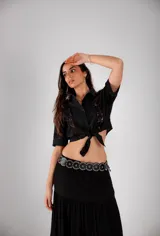 Camisa corta negra de manga corta con broderie en el frente y mangas. Se ata con un nudo en la parte delantera.