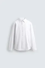 Camisa blanca de corte regular fit, con cuello italiano, manga larga con puños abotonados y cierre frontal con botones.