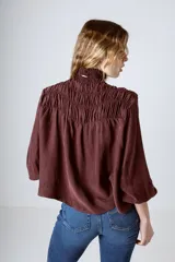 Blusa negra con cuello alto fruncido y mangas largas abullonadas con puños elásticos.