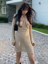 Vestido corto de crochet color crema, con mangas largas y cuello redondo.