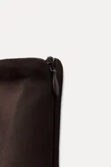 Top negro palabra de honor con escote recto y detalle de pieza metálica en forma de V forrada. Tiene falsos bolsillos con solapa en el delantero, forro interior combinado y cierre lateral con cremallera oculta.