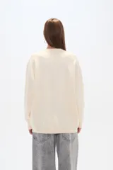 Sweater color crema, de corte holgado, con cuello redondo y mostacillas decorativas.