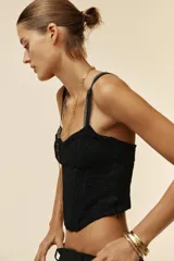 Top negro tipo corsetero con escote corazón y tirantes finos. Presenta varillas forradas que realzan la figura y cierre lateral con cremallera oculta.
