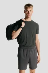 Short deportivo gris de tejido funcional de secado rápido con cintura elástica con cordón ajustable, bolsillos laterales y aberturas laterales en el bajo.