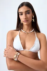 Top de bikini blanco con tirantes finos ajustables al cuello y a la espalda. Presenta volados en el escote y está confeccionado en tejido suave con acabado elástico.